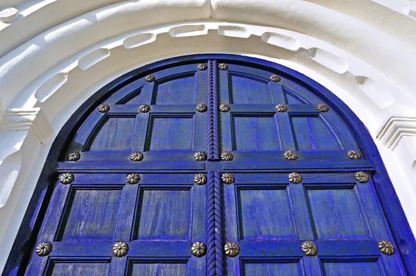 Architecture texture background. Aged wooden dark blue  door with metallic rivets