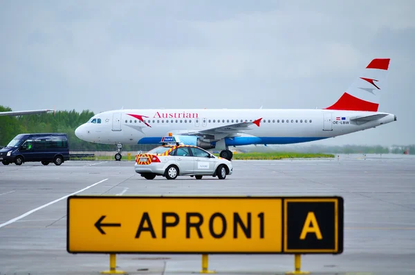 Austrian Airlines Airbus A320 aircraft and Follow me car on the runway of Pulkovo International airport in Saint-Petersburg, Russia