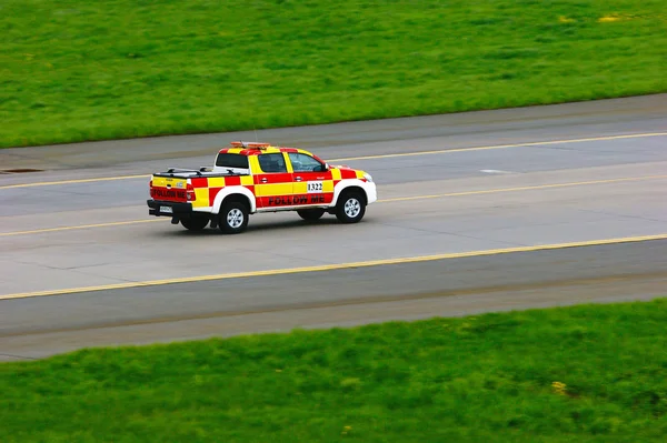 Red and yellow Follow Me car is riding the runway of Pulkovo International Airport