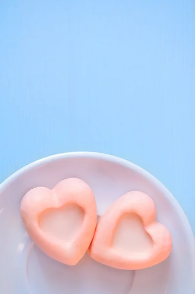 Heart-shaped pale orangesouffle cakes on the light blue wooden table. Selective soft focus on the cake and pastel processing.