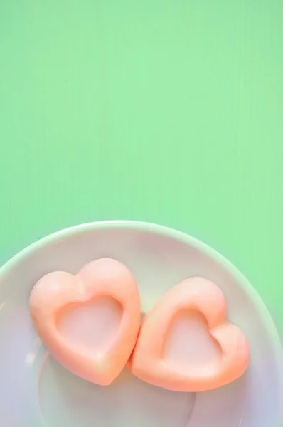 Heart-shaped pale orange souffle cakes on the green wooden table. Selective soft focus on the cake and pastel processing.