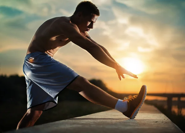 Image of a young athletic man stretching