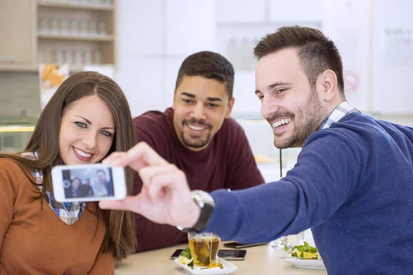 Group of young people laughing and doing a selfie in cafe