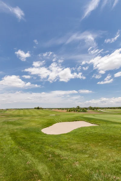 Golf course against cloudy sky