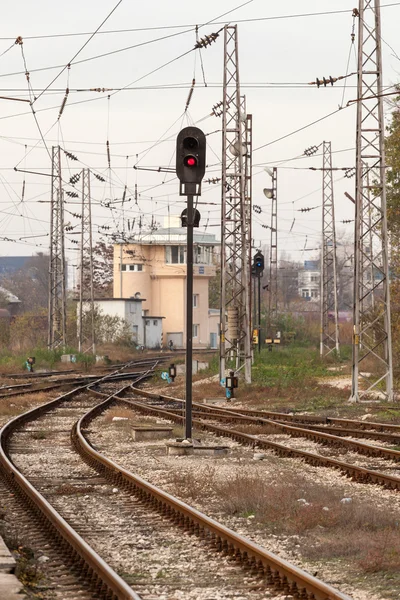 Red semaphore and railway tracks. Traffic light shows red signal on railway