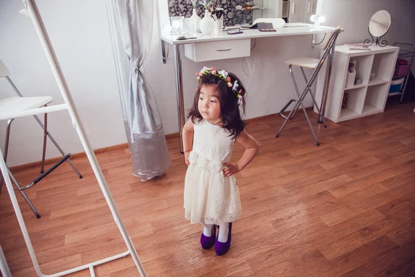 The little girl measures the mothers shoes in front of a mirror.