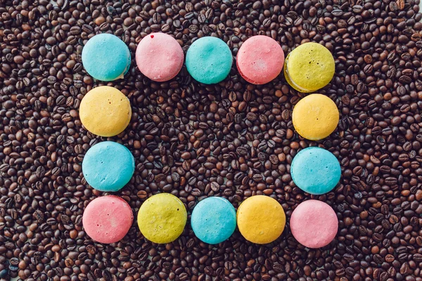 French macaroons laid out in a square on coffee beans background