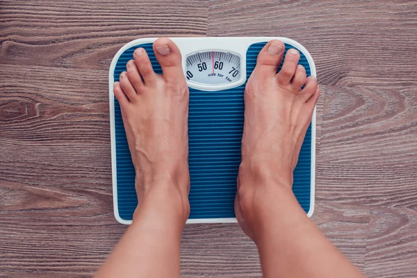 Girl is measuring her weight on the scales.