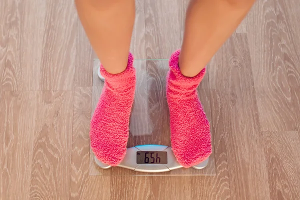 The girl in pink socks standing on weigher