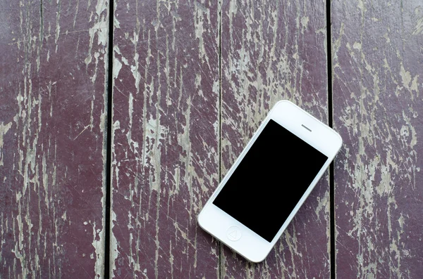 White smart phone with black screen on old dirty wooden backgrou