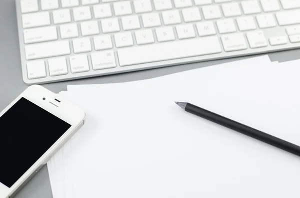 Blank paper with pencil and smart phone on Computer desk