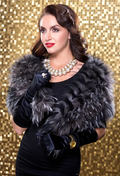 Portrait of elegant brunette retro woman wearing silver fox fur over gold mosaic background. Model looking at the side