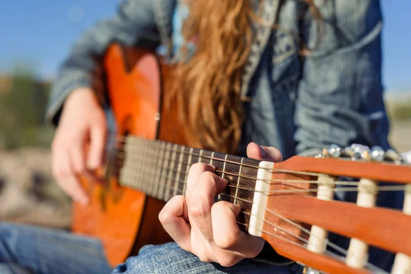 Close up shot without face. Woman playng guitar an the coast