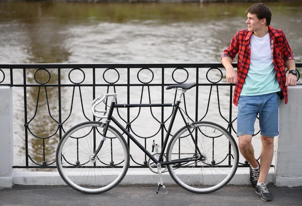 Hipster man with bicycle resting over quay
