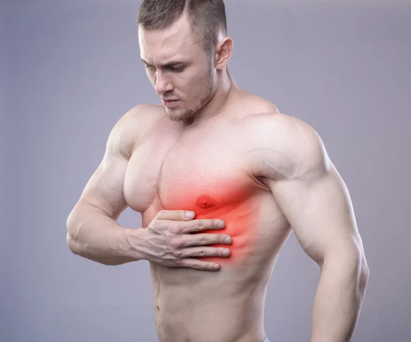 Athletic muscular man has pain in the heart. Red spot of injury
