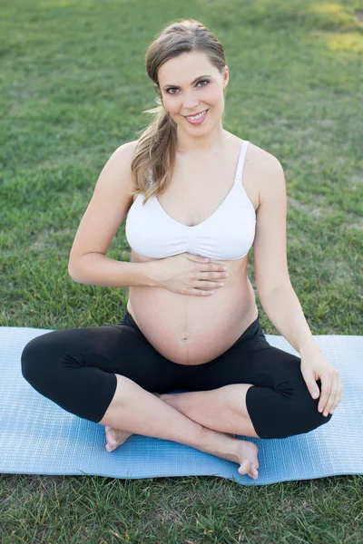 Pregnant woman doing yoga outside