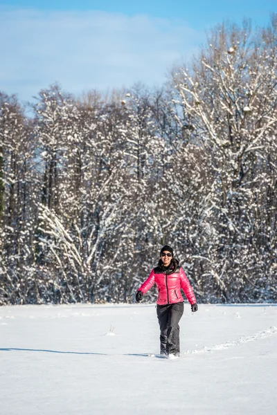 Young woman walking in a snow covered field