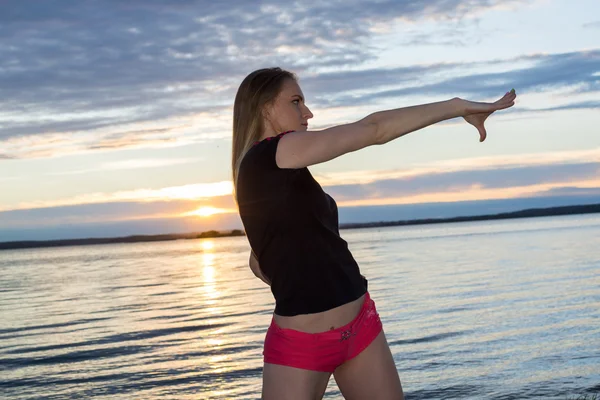 The blonde with a sporting figure does exercises in park