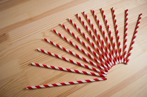 Striped cocktail straws on wooden background