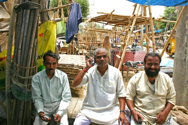 Delhi,India - July 9, 2004: Indian old men talking on his mobile phone at a roadside shop.