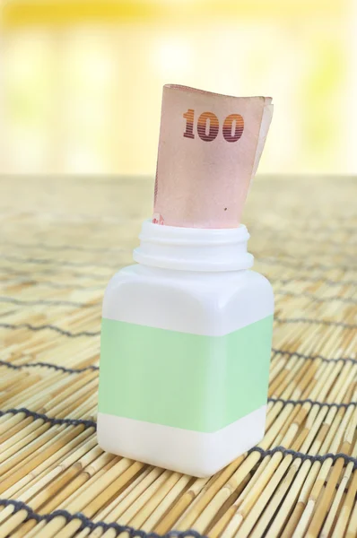 White pill bottle with Thai money note
