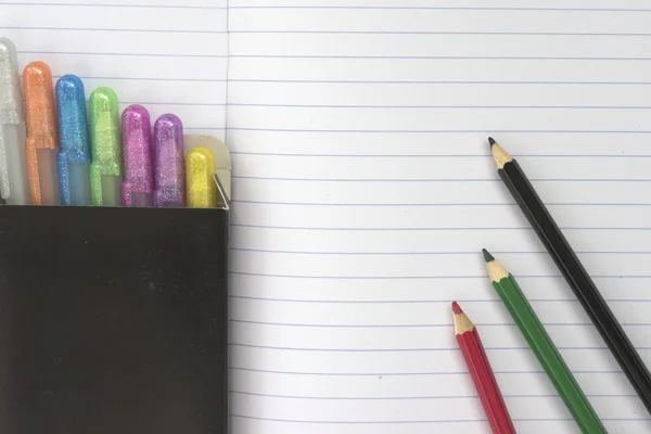 Notebook background with many colors pens and pencils