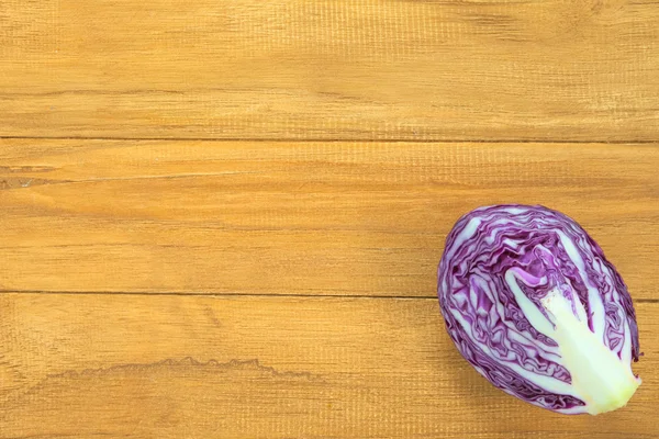 Quarter section of purple round cabbage over wooden background