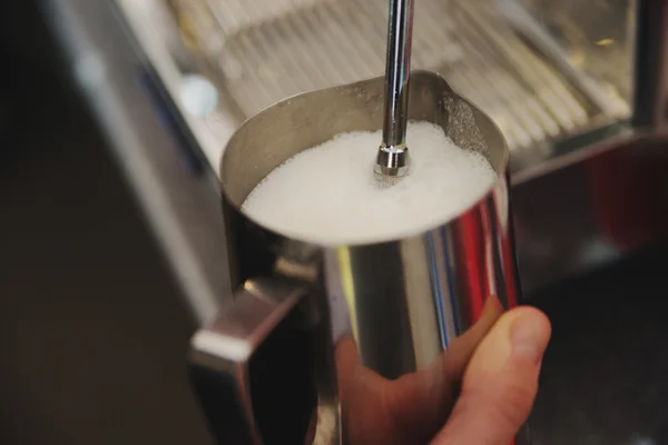 Coffee shop worker steams milk for a hot latte