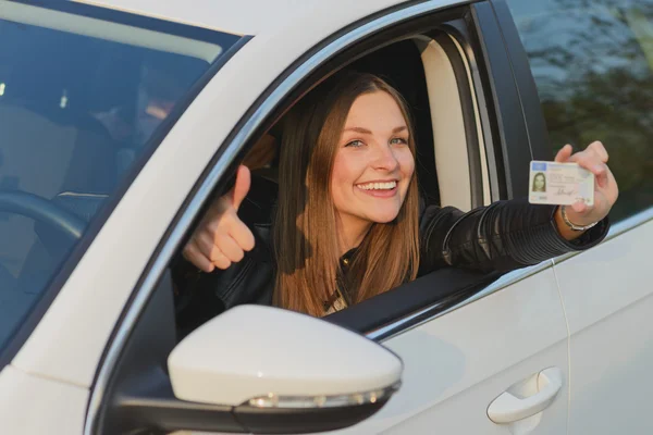 Attractive young woman proudly showing her drivers license