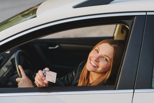 Attractive young woman proudly showing her drivers license