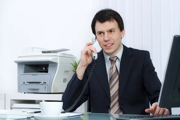 Business man in office speaks on telephone