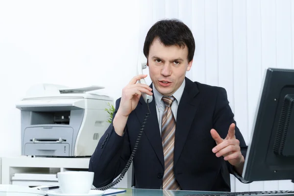 Business man in office speaks on telephone