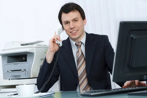 Business man in office speaks on telephone
