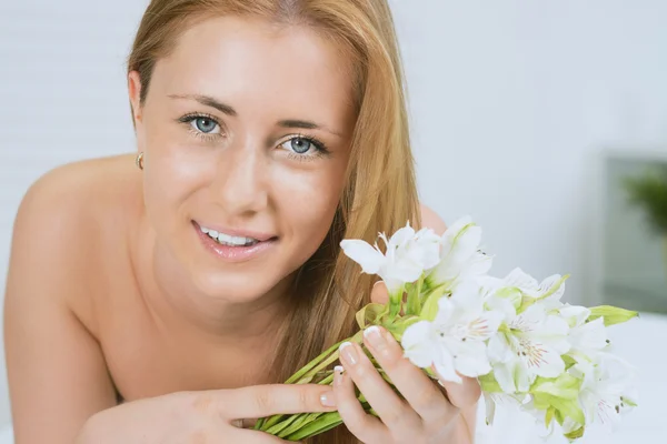 Portrait of beautiful woman with a flowers laying in spa