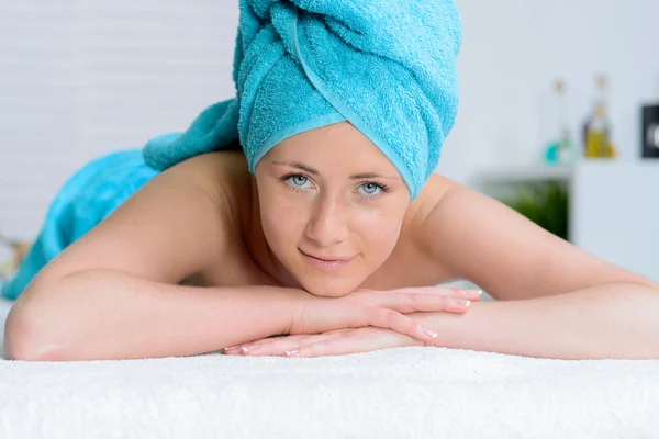 Beautiful woman wrapped in blue towel in massage salon