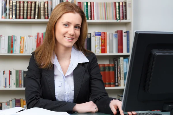 Pretty female student with pc and books working in a high schoo