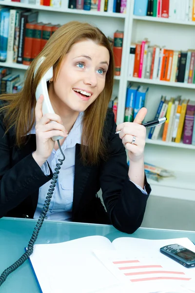 Attractive business woman speaking at telephone at the desk