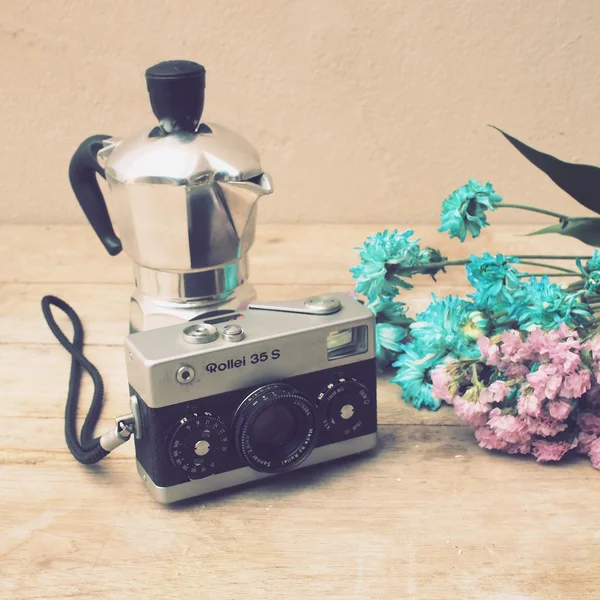 Vintage camera, teapot and flowers on wooden background