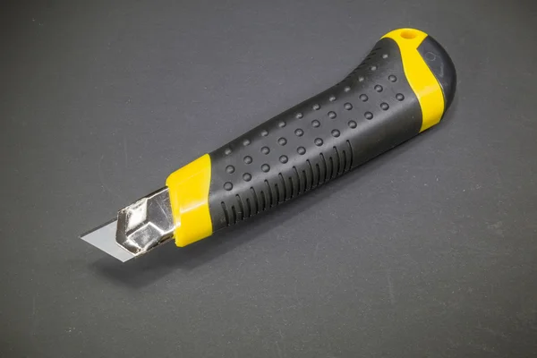 Utility knife with yellow plastic handle and black rubber insert