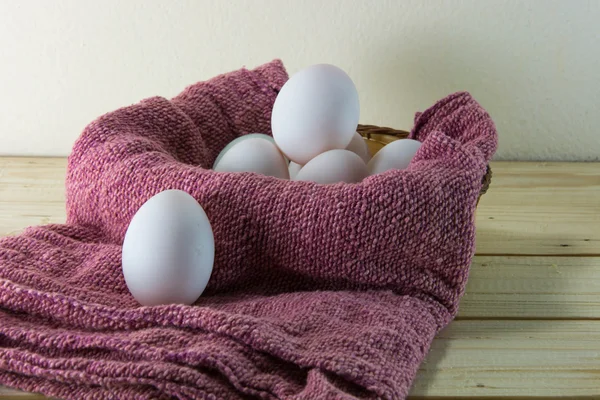 Fresh eggs in a woven basket with red dish towel. Selective focu