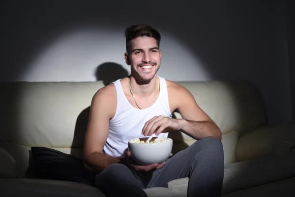 Young man eating popcorn and watching movies