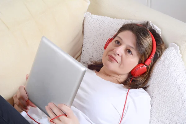 Woman listening music with digital tablet on the sofa.