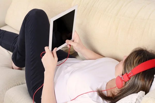 Woman listening music with digital tablet on the sofa.