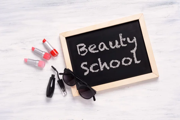 Chalkboard with Beauty School written on it, and cosmetic produc