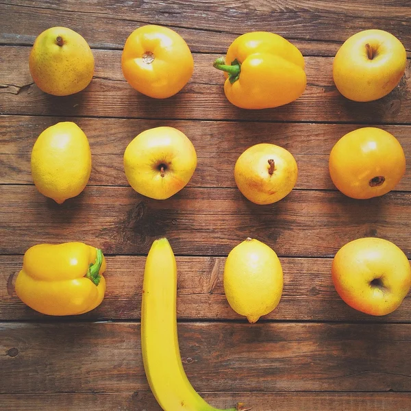 The yellow fruits and vegetables on a wooden background