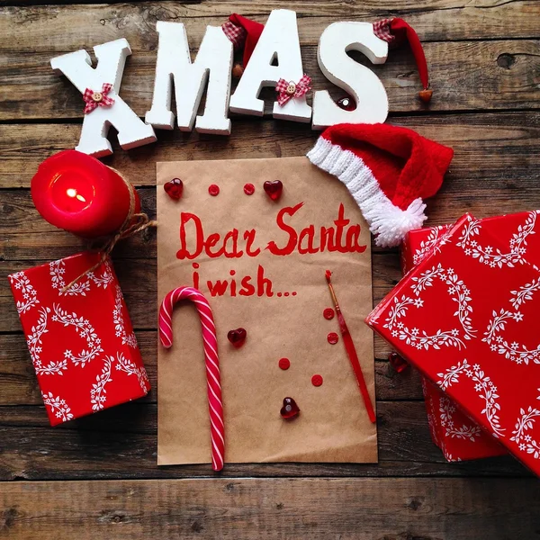 Letter to Santa and Christmas items over wooden background