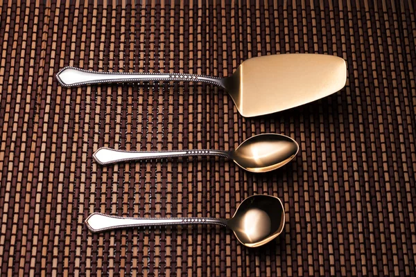 Silver shovel cake, teaspoon and spoon for sugar on the pattern table mat.