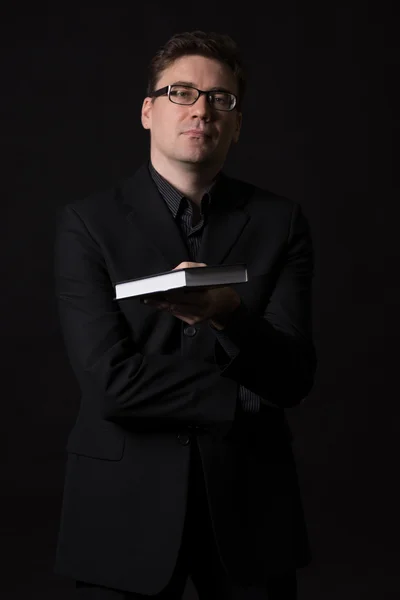 Man wearing a black suit presents a book to read