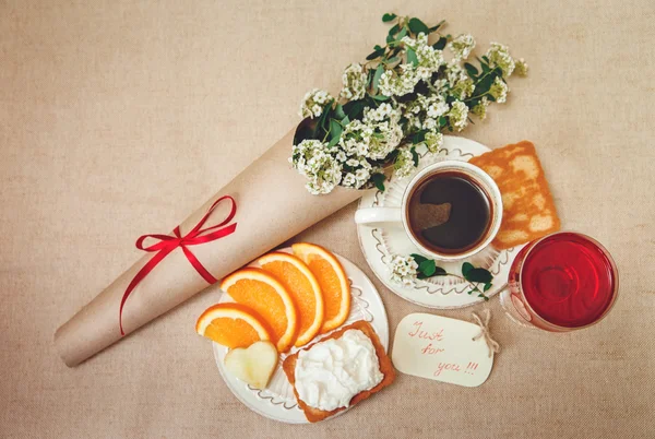 Romantic Birthday Breakfast.Cup of Coffee,Glass og red Beverage,Cut Orange,Biscuit with Cottage Cheese.Wish Card with Flowers.Top View.Toned