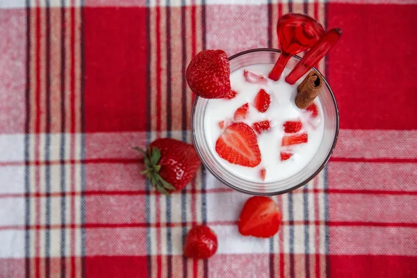 Two Glasses of Milk Cocktail,Red Fresh Strawberries with Plastic Spoons and Cinnamon on the Check Tablecloth.Breakfast Organic Healthy Tasty Food.Cooking Vitamins Ingredients.Summer Fruits